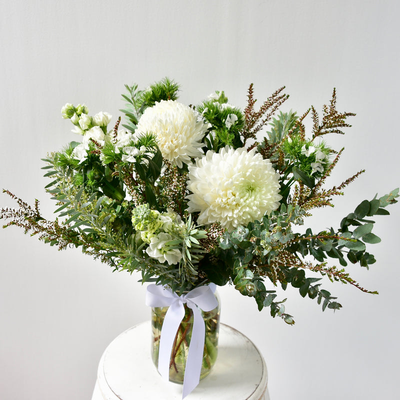 A pretty posy of seasonal blooms, in a mason jar tied with a bow.  Includes what&
